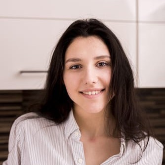 moteris su tamsiais plaukais besišypsanti